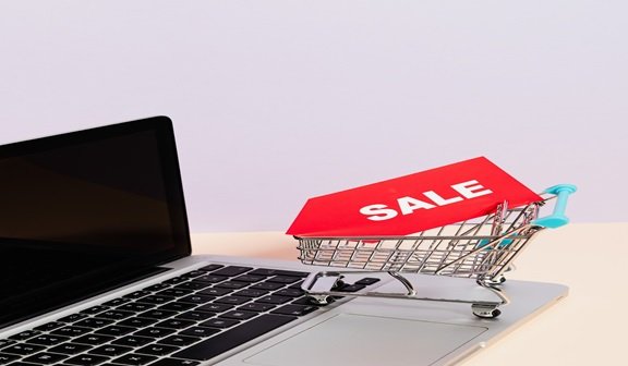 Miniature cart on a laptop displaying online sales
