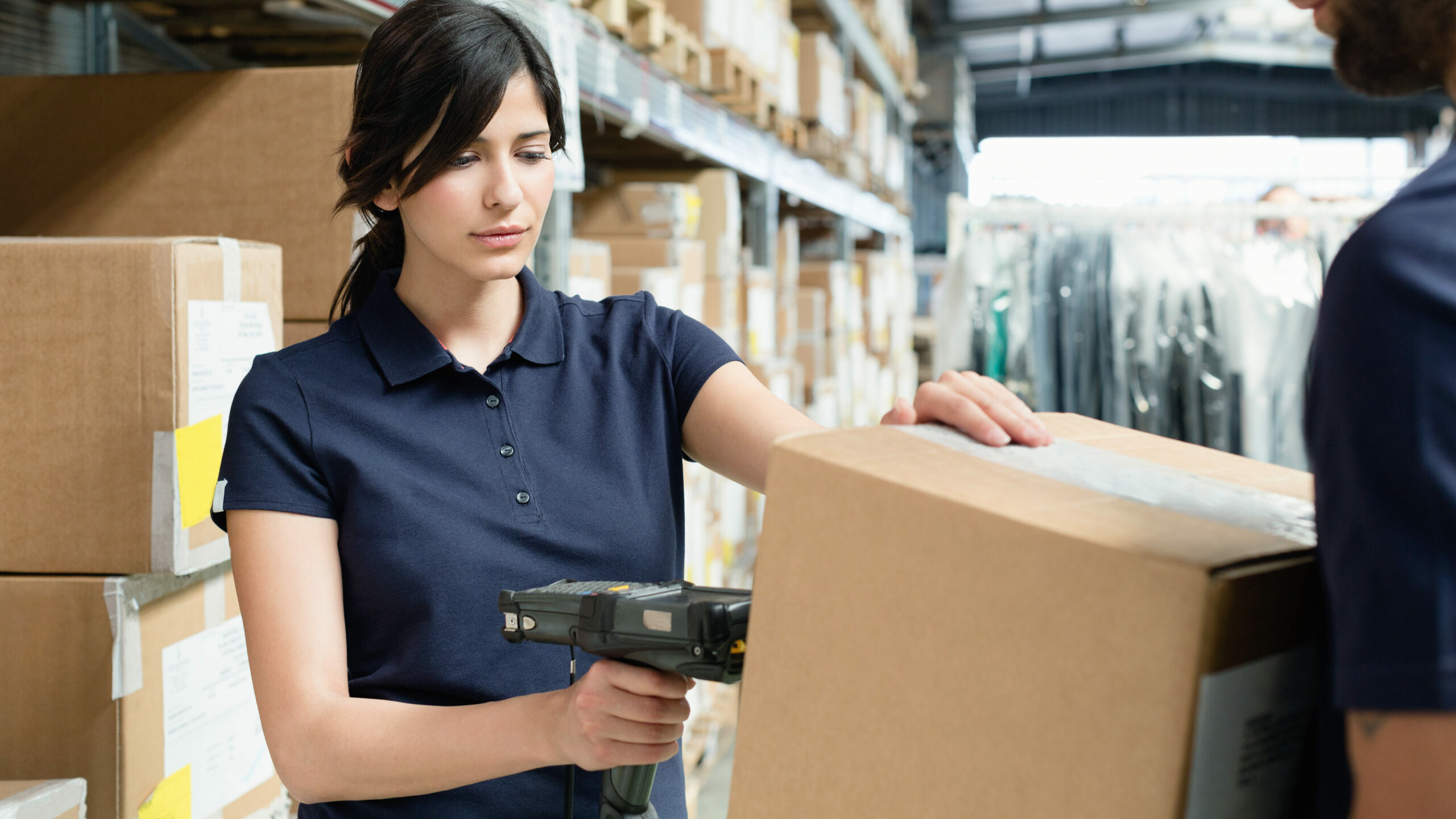 Warehouse Workers Using Barcode Scanner On Box In Distribution Warehouse