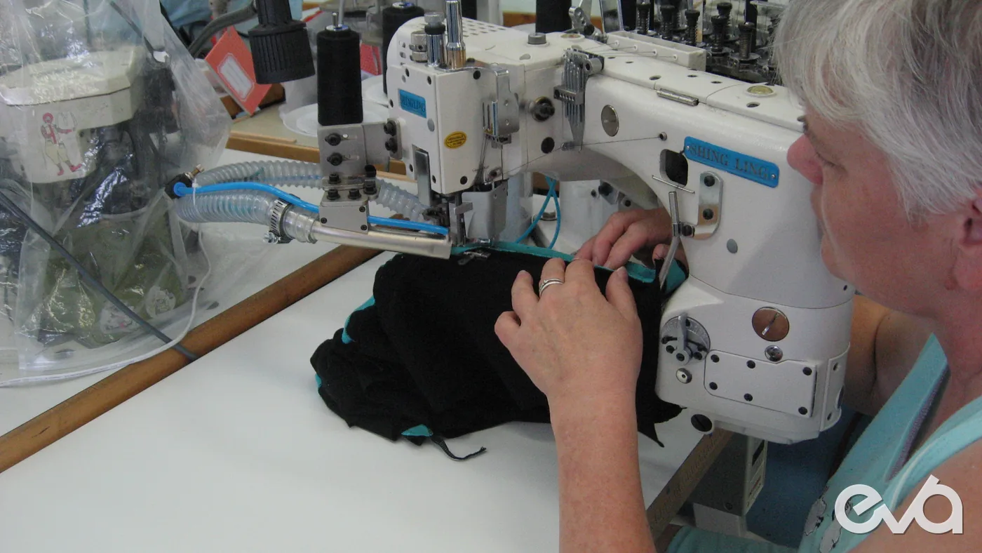 Operator reviewing stitching quality on industrial sewing machine